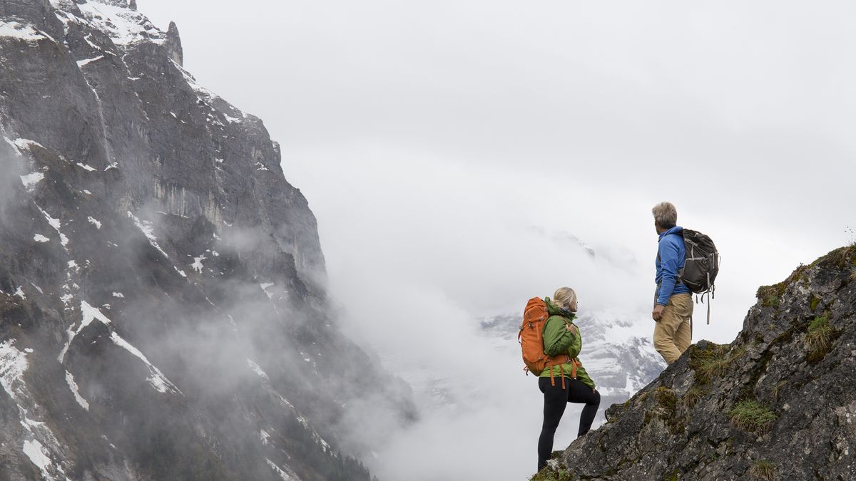 Create an image of eco-friendly outdoor clothing displayed in a picturesque natural environment. Clothing items include jackets, hiking boots, and backpacks made from sustainable materials. The backgr